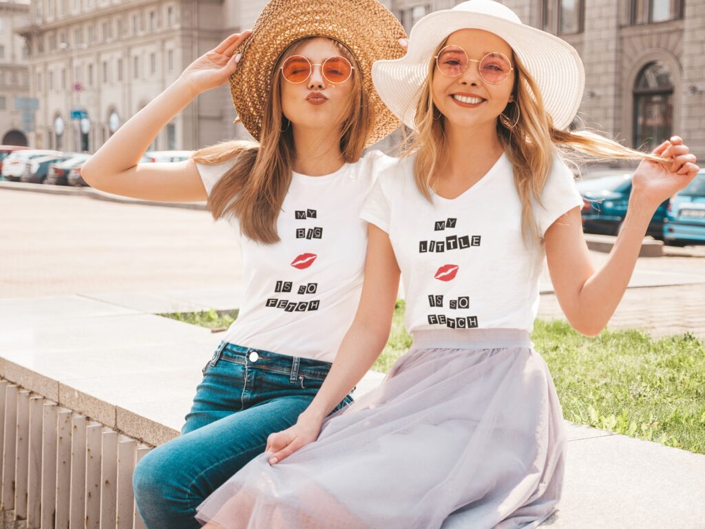 in same tshirt two femake posing at a city