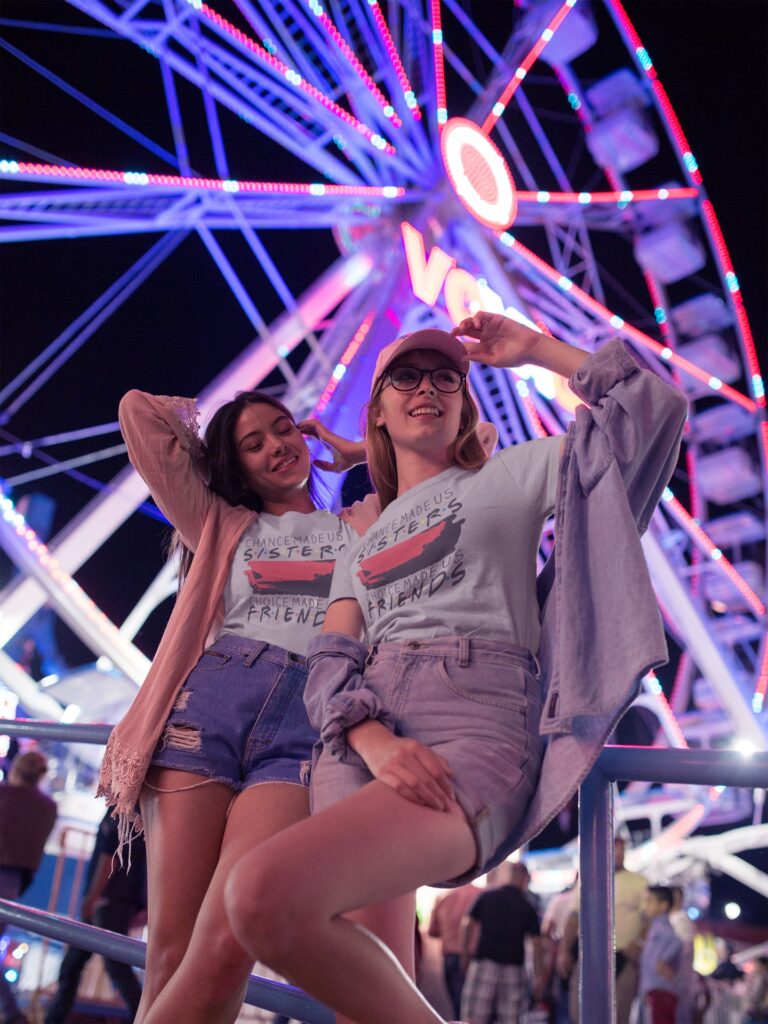 Two girls Wearing Tshirts mockuo near a ferris wheel at night